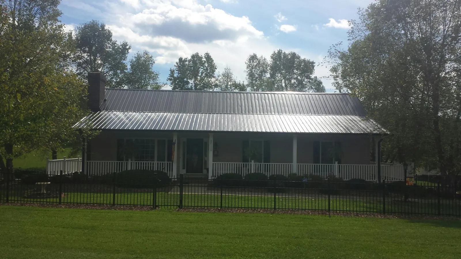 Gray metal roof on a brick ranch with a full width front porch — Gutter Guard Installation work by our crew in Beverly